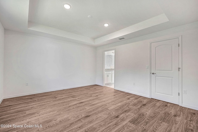 empty room featuring light hardwood / wood-style flooring and a raised ceiling