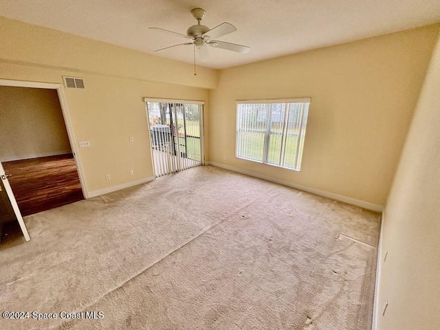 carpeted empty room with a wealth of natural light and ceiling fan