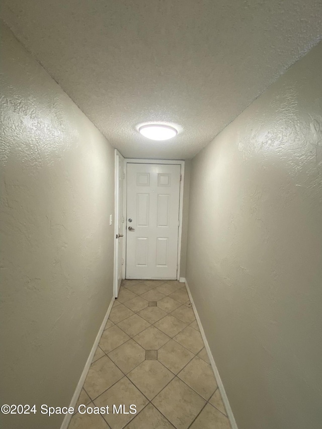 hallway with light tile patterned floors and a textured ceiling