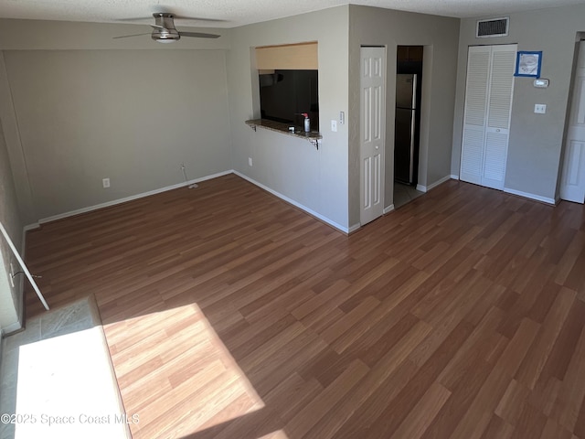 unfurnished living room featuring dark wood-type flooring, a textured ceiling, and ceiling fan