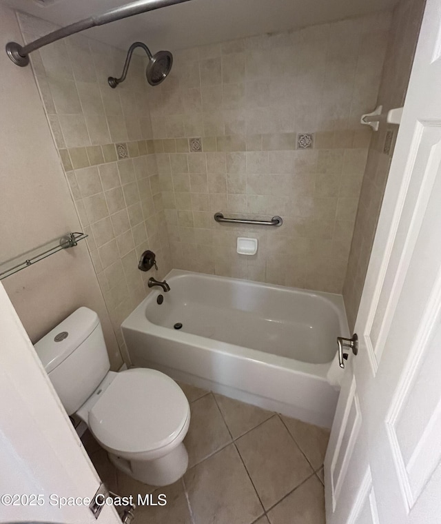 bathroom with tile patterned flooring, tiled shower / bath, and toilet