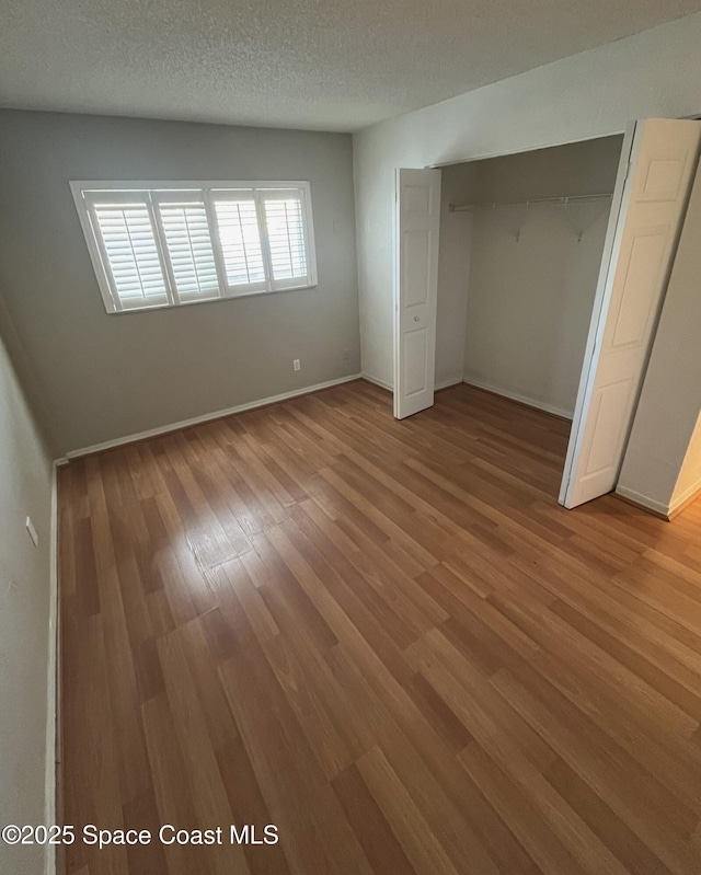 unfurnished bedroom with hardwood / wood-style flooring, a closet, and a textured ceiling