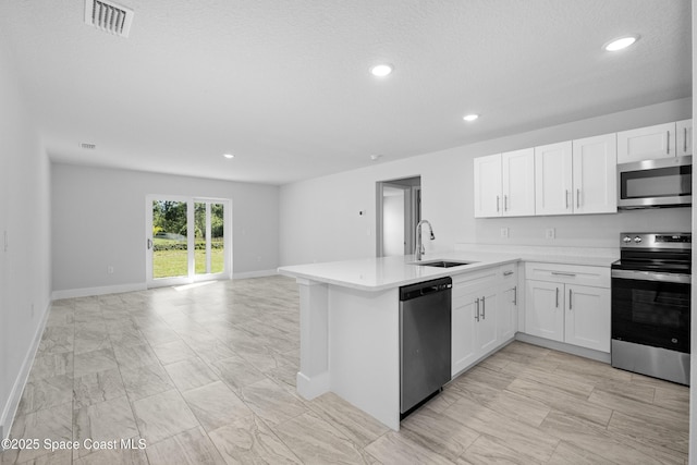 kitchen featuring stainless steel appliances, a textured ceiling, white cabinets, sink, and kitchen peninsula