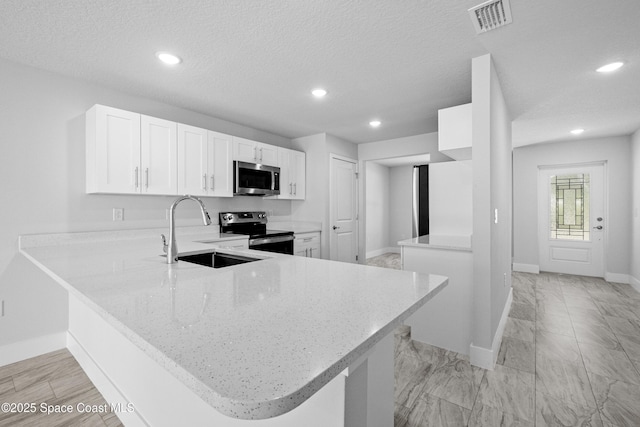 kitchen featuring sink, kitchen peninsula, appliances with stainless steel finishes, and white cabinetry