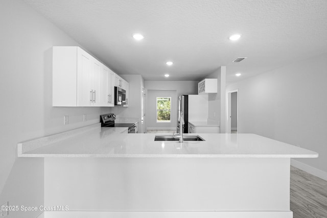 kitchen with white cabinetry, kitchen peninsula, stainless steel appliances, sink, and a textured ceiling