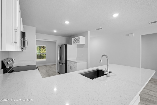 kitchen featuring light hardwood / wood-style flooring, stainless steel appliances, sink, white cabinetry, and kitchen peninsula