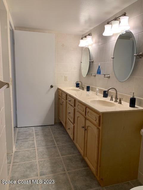 bathroom with tile patterned floors, vanity, and tile walls