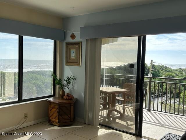 doorway featuring a water view and light tile patterned floors