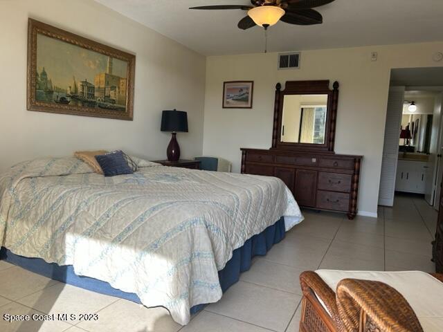 tiled bedroom with ceiling fan and connected bathroom