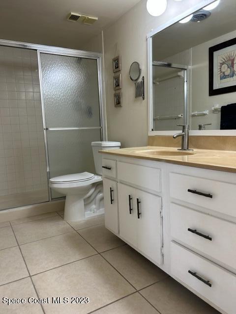 bathroom featuring tile patterned floors, vanity, a shower with shower door, and toilet