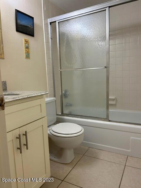 full bathroom with tile patterned flooring, vanity, combined bath / shower with glass door, and toilet