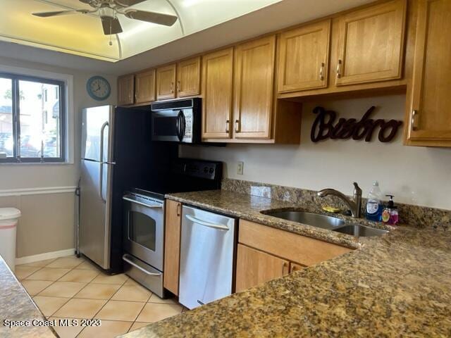 kitchen featuring dark stone counters, sink, ceiling fan, light tile patterned flooring, and stainless steel appliances