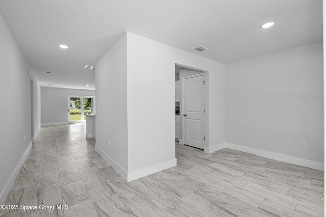 spare room featuring recessed lighting, visible vents, and baseboards