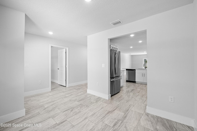 empty room with recessed lighting, visible vents, a textured ceiling, and baseboards