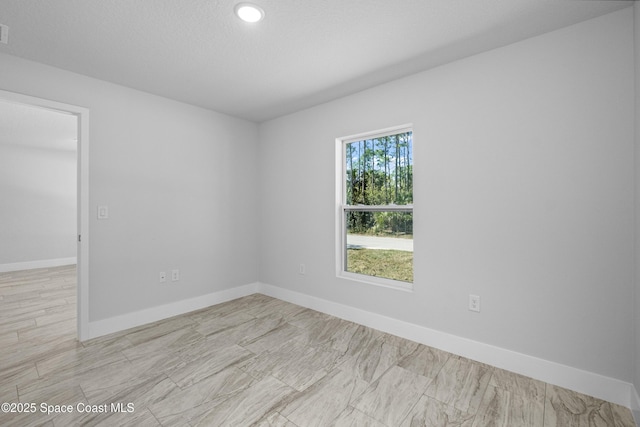 spare room featuring visible vents, baseboards, and a textured ceiling