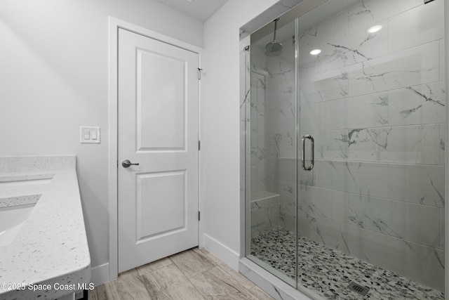 full bathroom with double vanity, a marble finish shower, and baseboards