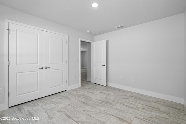 unfurnished bedroom with a closet, visible vents, and baseboards