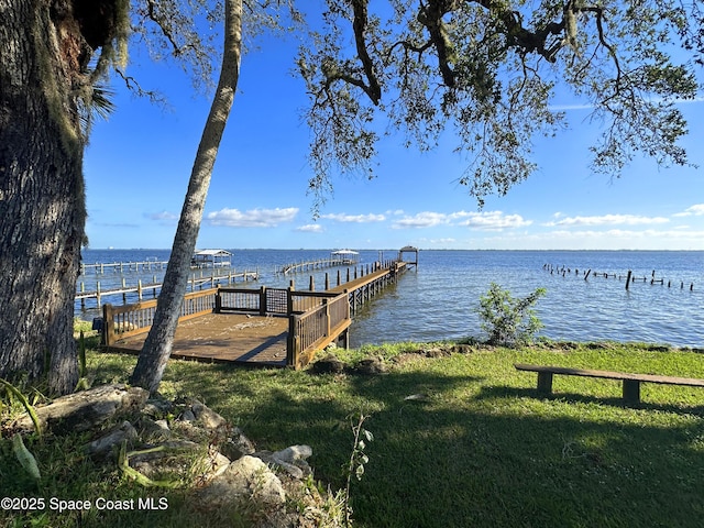 dock area with a lawn and a water view