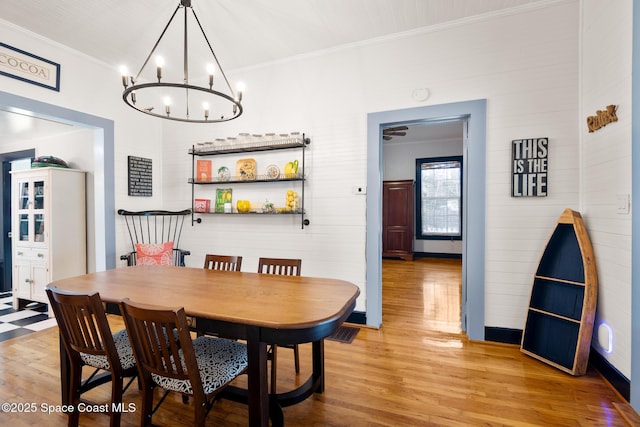 dining space featuring a chandelier, ornamental molding, and light hardwood / wood-style floors