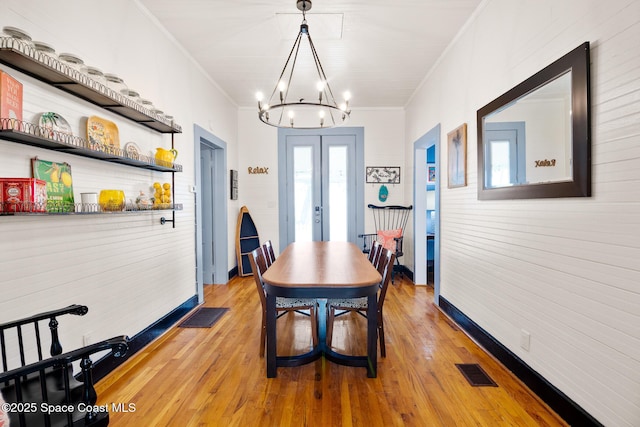 dining room with hardwood / wood-style flooring, ornamental molding, and a chandelier