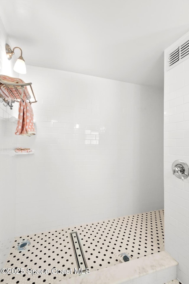 bathroom with a tile shower and tile patterned floors