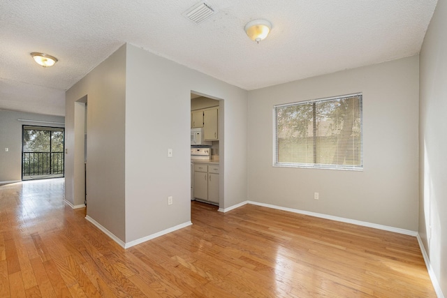 empty room with a textured ceiling and light hardwood / wood-style floors