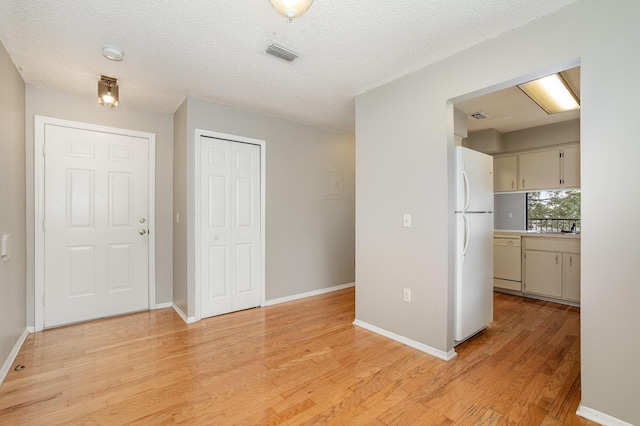 interior space featuring a textured ceiling and light hardwood / wood-style flooring