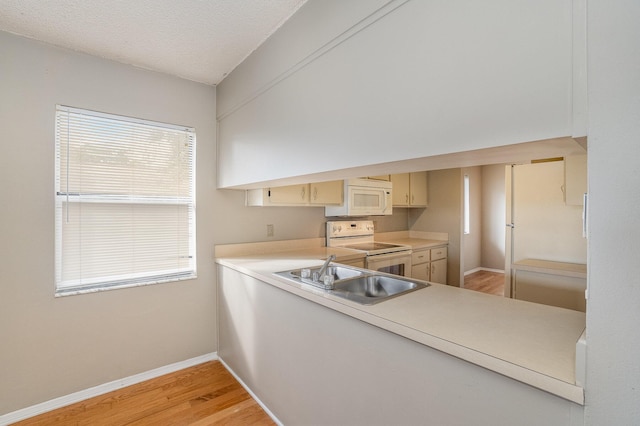 kitchen featuring a textured ceiling, white appliances, sink, light hardwood / wood-style flooring, and cream cabinetry