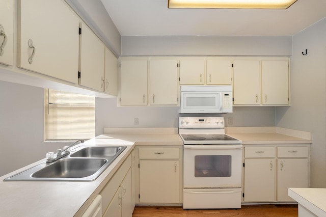 kitchen with cream cabinetry, white appliances, light hardwood / wood-style floors, and sink