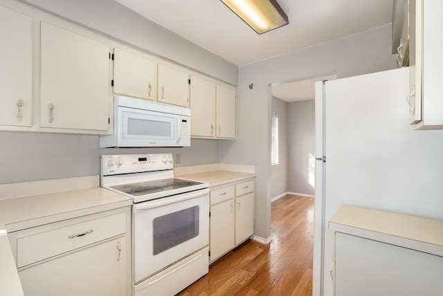 kitchen with light hardwood / wood-style floors, white appliances, and cream cabinetry