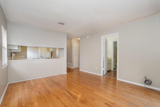 unfurnished room featuring light hardwood / wood-style floors and a textured ceiling