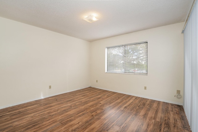 spare room featuring dark hardwood / wood-style flooring and a textured ceiling