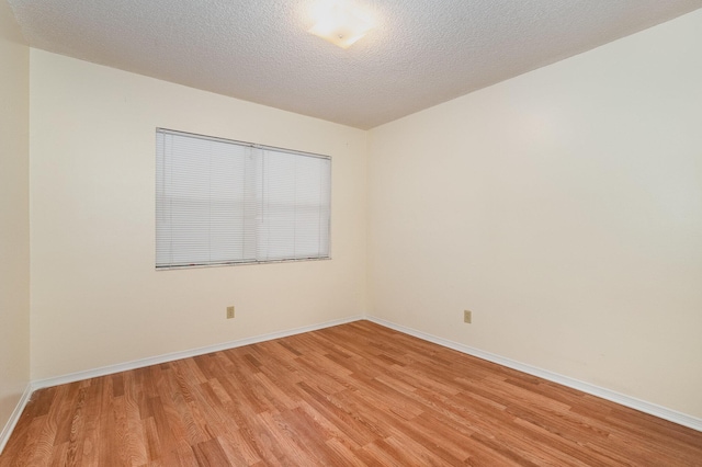 unfurnished room featuring light hardwood / wood-style floors and a textured ceiling