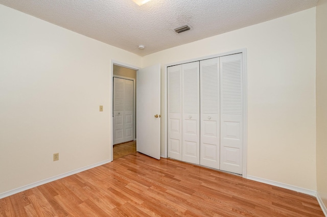 unfurnished bedroom featuring a textured ceiling, light hardwood / wood-style floors, and a closet