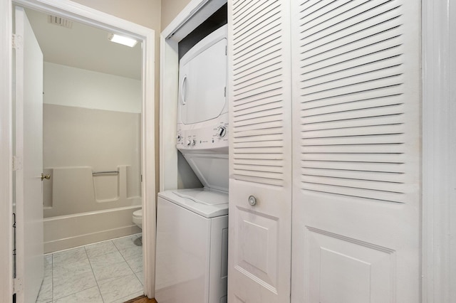 washroom with light tile patterned flooring and stacked washer and clothes dryer