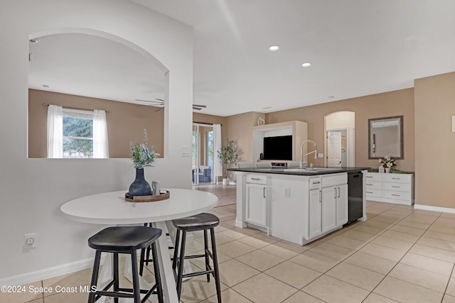 kitchen with ceiling fan, sink, light tile patterned flooring, a kitchen island with sink, and white cabinets