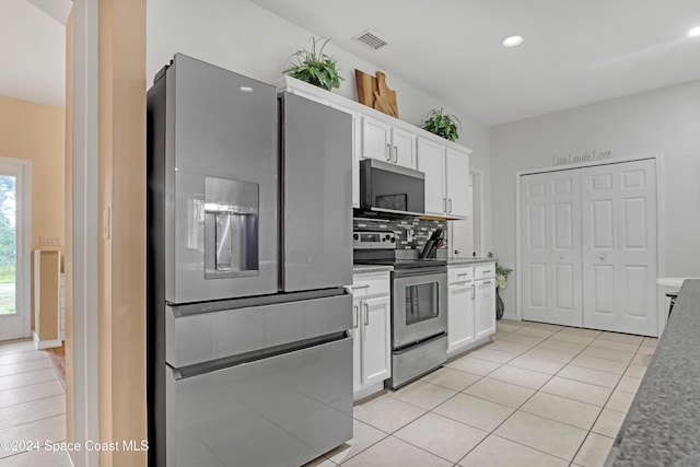 kitchen with tasteful backsplash, white cabinets, stainless steel appliances, and light tile patterned floors