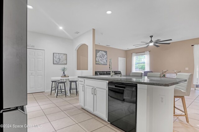 kitchen with dishwasher, ceiling fan, a kitchen island, white cabinetry, and a breakfast bar area