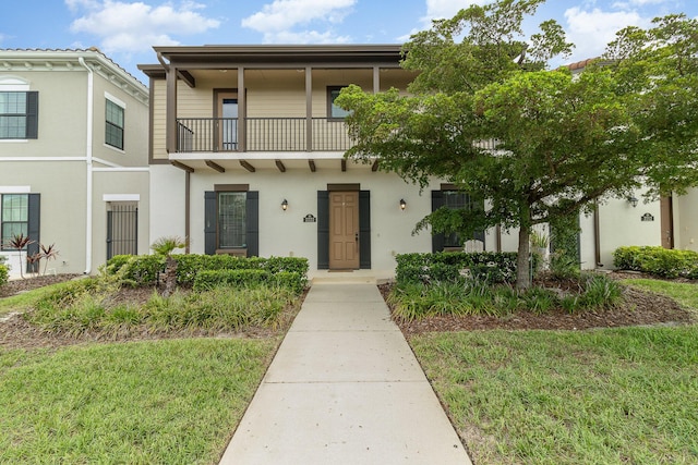 view of front of house featuring a balcony and a front lawn