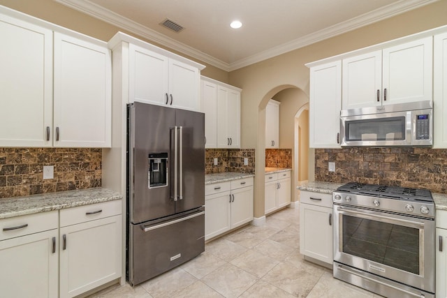 kitchen with premium appliances, white cabinetry, light stone countertops, and decorative backsplash