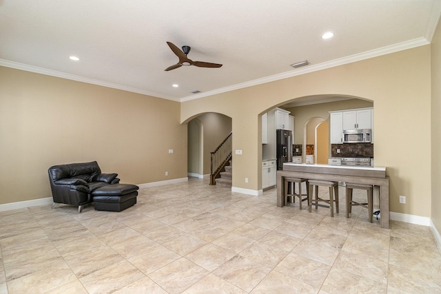 living area with ceiling fan and ornamental molding