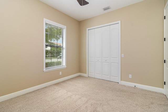 unfurnished bedroom featuring ceiling fan, a closet, and carpet