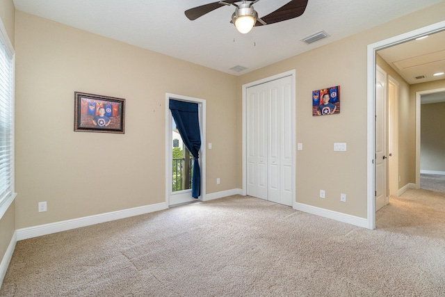 unfurnished bedroom featuring ceiling fan, light colored carpet, and a closet