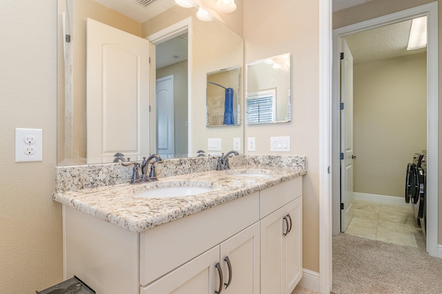 bathroom featuring tile patterned floors, vanity, and washing machine and clothes dryer