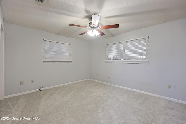 spare room featuring ceiling fan, light colored carpet, and a textured ceiling