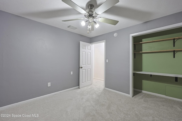 unfurnished bedroom featuring ceiling fan, a closet, and light colored carpet