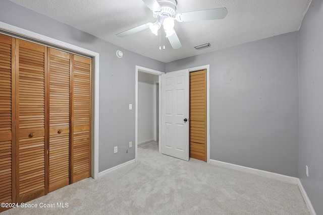 unfurnished bedroom with ceiling fan, a textured ceiling, and light carpet