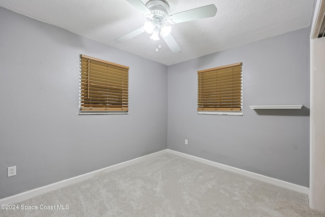 unfurnished room featuring ceiling fan, light colored carpet, and a textured ceiling