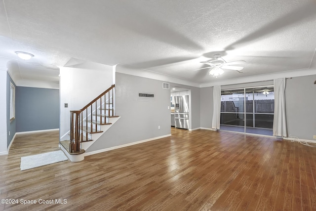 unfurnished living room featuring hardwood / wood-style floors, ceiling fan, and a textured ceiling