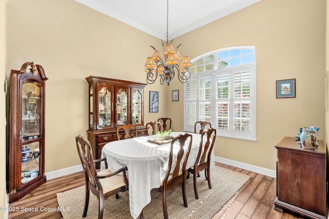 dining room with hardwood / wood-style floors, crown molding, and a notable chandelier